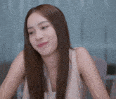 a woman with long brown hair is sitting at a table and making a funny face