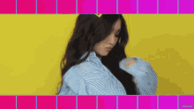 a woman in a blue and white striped shirt is standing in front of a yellow and pink background .