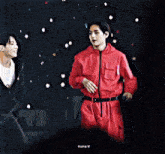 a couple of men are standing next to each other on a stage and talking to each other .