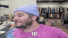 a man with a beard wearing a purple shirt and a purple beanie says 14