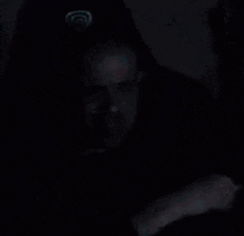 a bald man is sitting in a chair in a dark room .