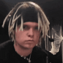 a young man with dreadlocks is wearing a headband and headphones .