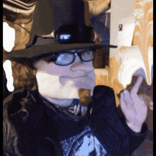 a man wearing glasses and a top hat giving the middle finger