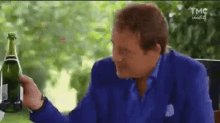 a man in a blue suit is holding a bottle of champagne