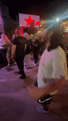 a group of people are dancing in front of a sign that says red star