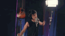 a man is singing into a microphone in front of a guitar