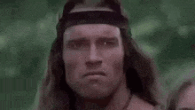 arnold schwarzenegger is wearing a headband and making a serious face .
