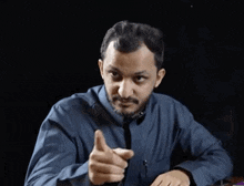 a man in a blue shirt and tie is pointing
