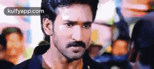 a close up of a man with a mustache looking at the camera .