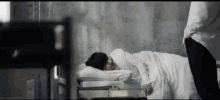 a woman is laying in a hospital bed with a man standing behind her .