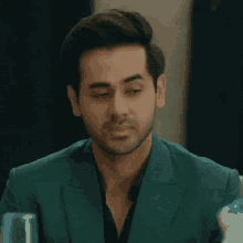 a man with his eyes closed is wearing a green suit and black shirt
