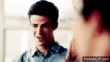 a young man in a plaid shirt is smiling and talking to another man .