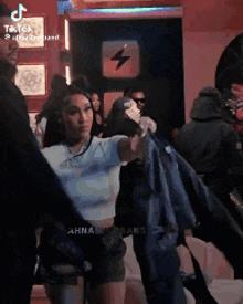 a woman is holding a blue jacket in her hands in a crowd of people .