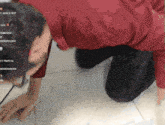 a man in a red shirt is kneeling down on a tiled floor