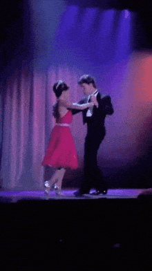 a man in a tuxedo is dancing with a woman in a pink dress