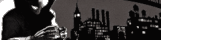 a black and white photo of a man talking on a cell phone in front of a city skyline