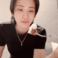 a woman wearing a black shirt and a silver necklace is holding a small mouse