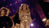 a woman in a gold bodysuit sings into a microphone on a stage