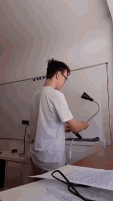 a man is sitting at a desk holding a lamp in front of a white board