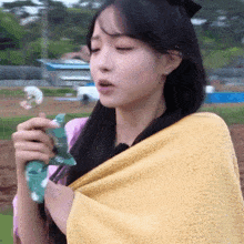 a woman wrapped in a yellow towel is blowing bubbles