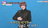 a man with red hair is standing in front of a blue background with korean writing on it .