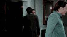 a man is standing in front of a bookshelf in a dark room with a mirror .