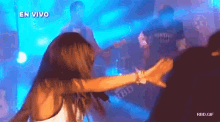 a woman is dancing in front of a man playing a guitar with the words en vivo written above her