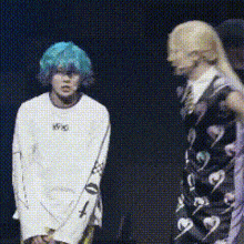 a man with blue hair is standing next to a woman in a black and white dress