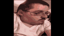 a man with glasses and a mustache is wearing a white shirt and looking at the camera .