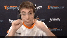 a man wearing headphones stands in front of a wall with miami heretics written on it