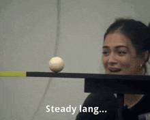 a woman is balancing a ball on a beam with the words " steady lang " below her