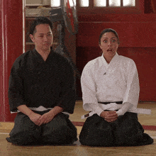 a man and a woman in martial arts uniforms are kneeling down on the floor