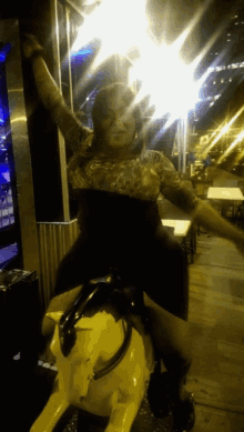 a woman riding on the back of a yellow bull
