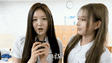 two girls are standing next to each other and one is holding a sony microphone in her hand .