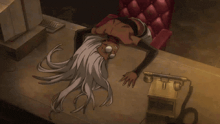 a woman with long white hair is laying on a desk next to a telephone