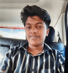 a young man wearing a striped shirt is sitting in the back seat of a car