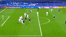 a group of soccer players are playing on a field with a mastercard ad in the background