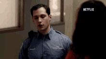 a man in a uniform is talking to a woman in an orange prison uniform .