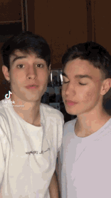 two young men are standing next to each other and one of them has a nose ring .