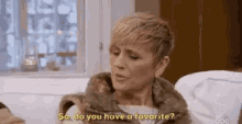 a woman in a fur coat is sitting on a couch and talking to someone .