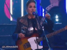 a woman singing into a microphone while playing a guitar with the hashtag lialmeida05