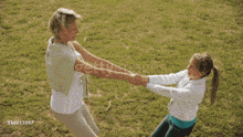 a woman is holding a girl 's hand in a field with the number 156611097 on the bottom