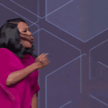 a woman in a pink dress is singing into a microphone on a stage