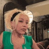 a woman with blonde hair and a green tank top has a tattoo on her chest that says " i love you "