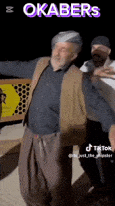 two men are dancing in front of a sign that says okabers on it