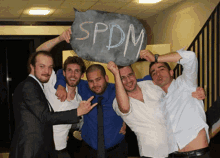 a group of men holding a sign that says spdm on it