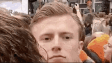 a man is standing in a crowd of people and taking a selfie .