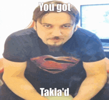 a man with a beard wearing a superman t-shirt says you got takla 'd