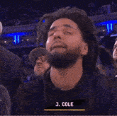 a man with dreadlocks is wearing a black shirt with the name j. cole on it