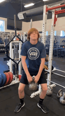 a man in a blue vans shirt is lifting a kettlebell